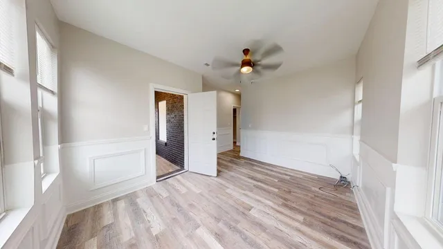 a view of empty room with wooden floor and fan