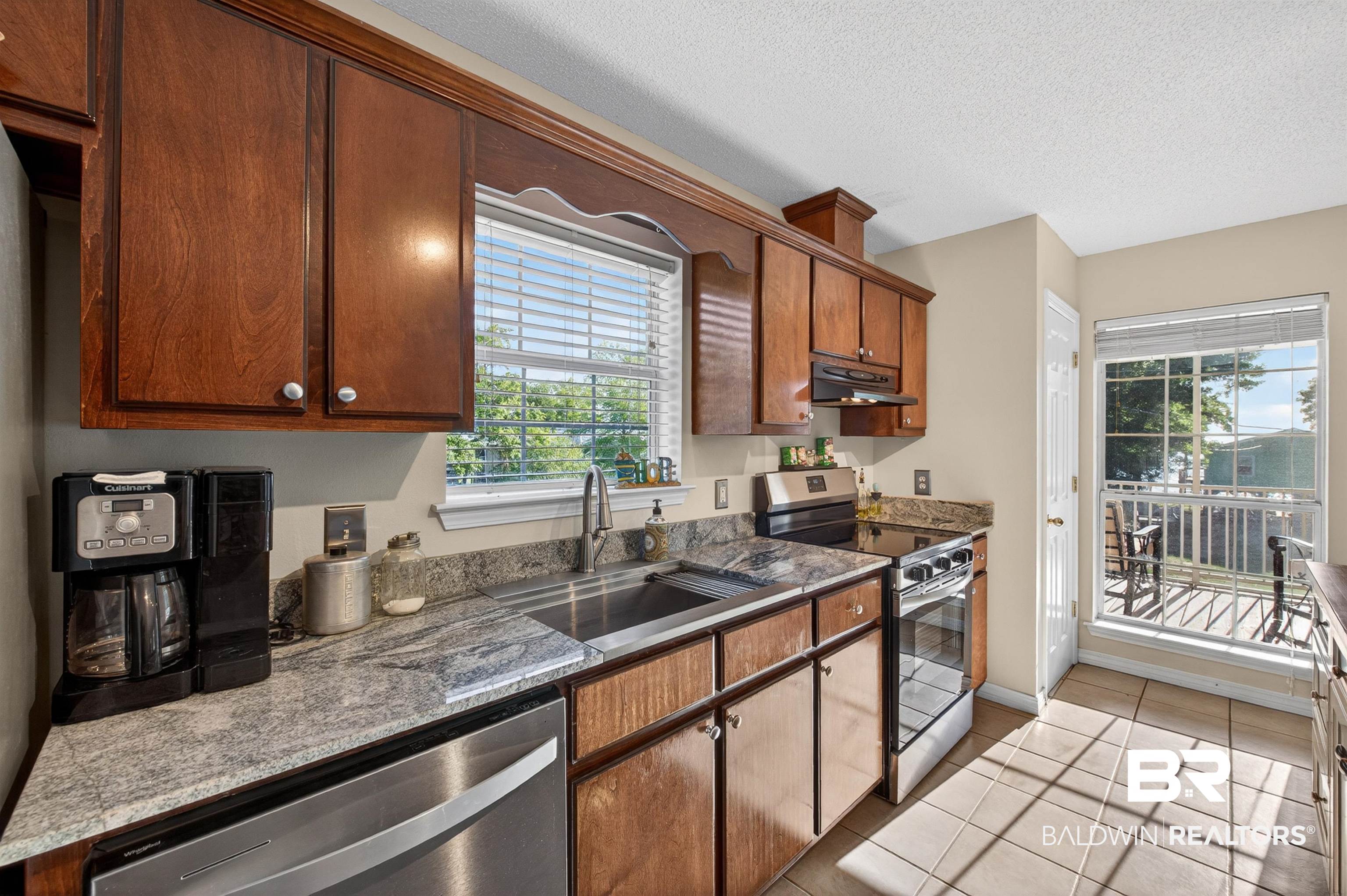 9624 North Bay Street Foley, AL 36535 - Photo 12 of 59 Kitchen featuring wood cabinetry, light-toned granite-style countertops, stainless steel appliances, and a tile floor
