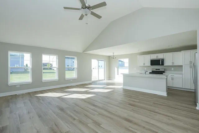 a view of a kitchen with kitchen island a sink wooden floor and a living room