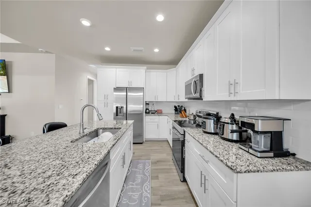 a large kitchen with granite countertop a large counter top appliances and cabinets