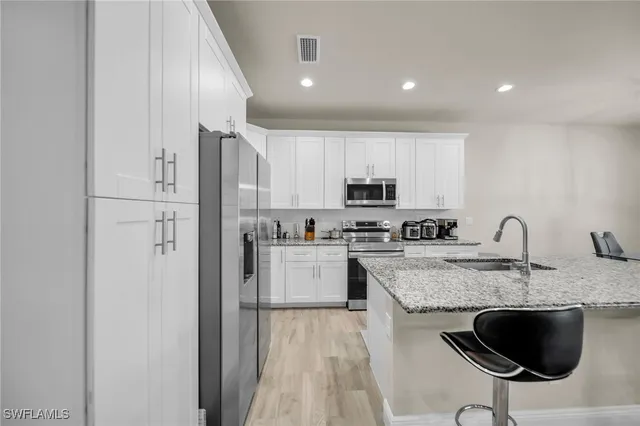 a kitchen with stainless steel appliances granite countertop a sink refrigerator and cabinets
