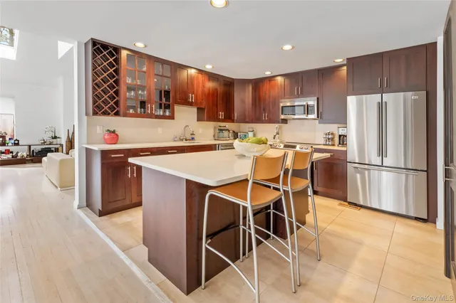 a kitchen with stainless steel appliances kitchen island granite countertop a refrigerator oven a sink dishwasher and white cabinets with wooden floor
