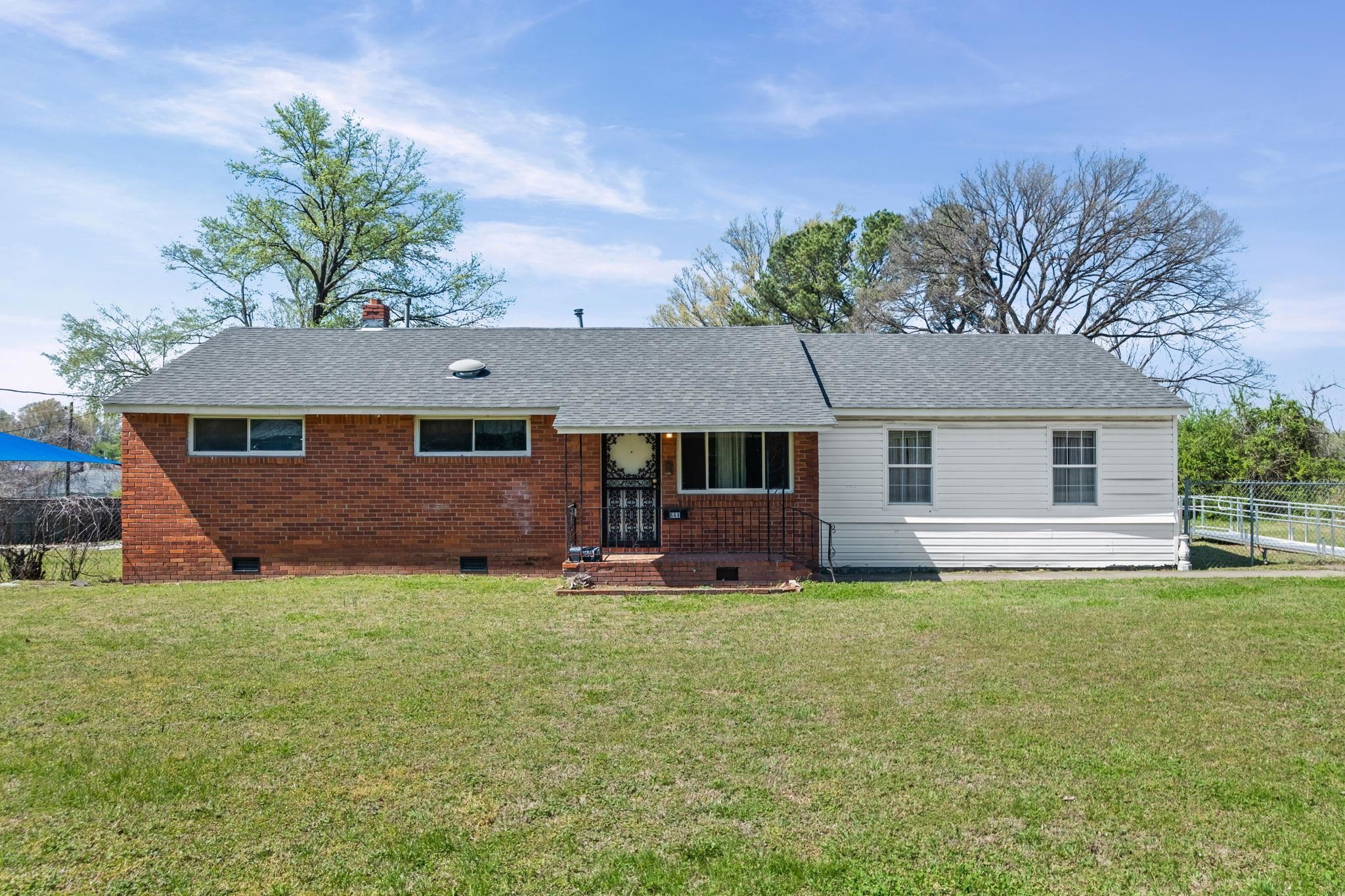 View of front facade with crawl space, roof with shingles, brick siding, and a chimney