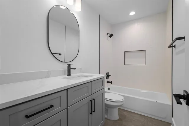a bathroom with a granite countertop toilet a sink and a mirror