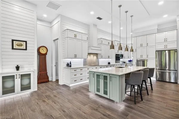 a large kitchen with stainless steel appliances granite countertop a lot of counter space and wooden floors