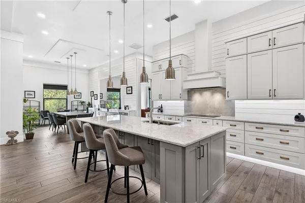 a kitchen with stainless steel appliances kitchen island granite countertop a table chairs stove and white cabinets