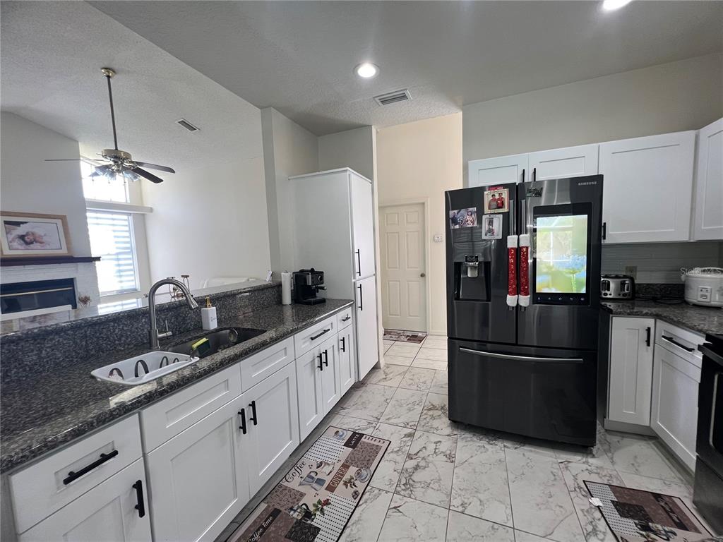 14189 Cornewall Lane Spring Hill, FL 34609 - Photo 13 of 36 a kitchen with granite countertop a refrigerator and a sink