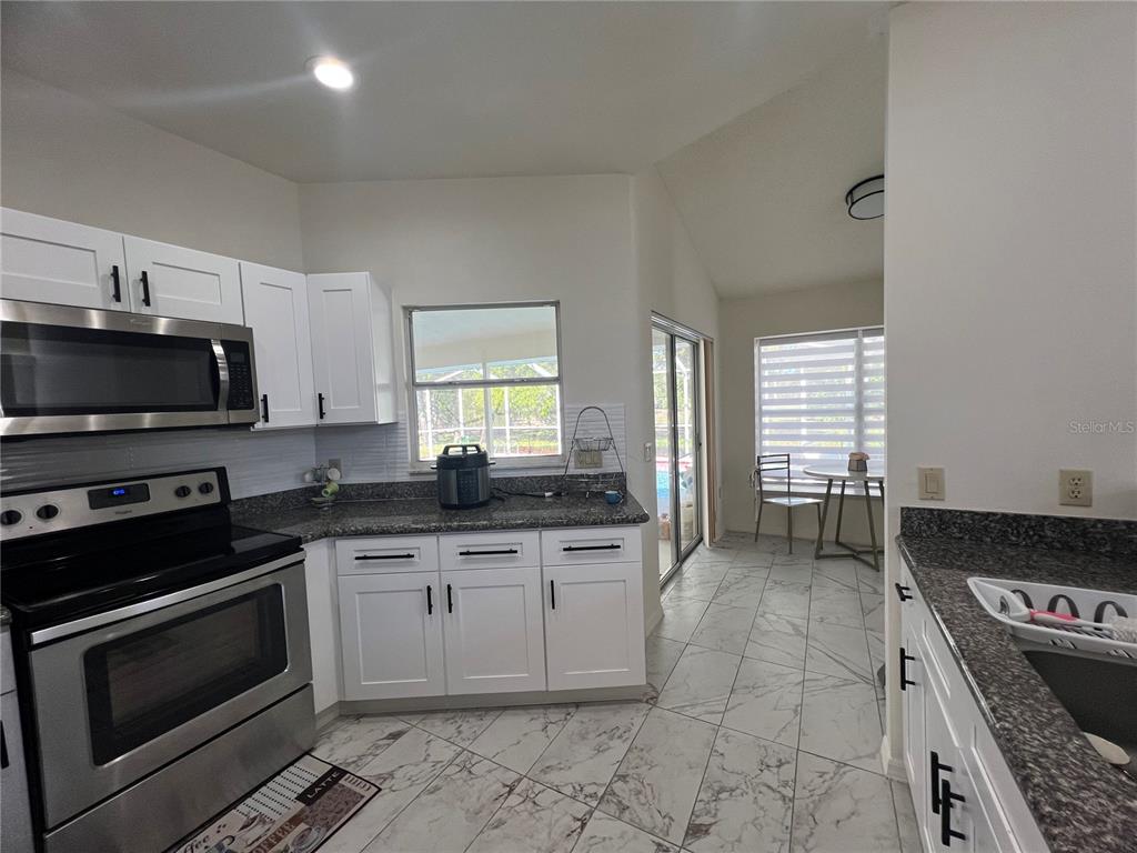 14189 Cornewall Lane Spring Hill, FL 34609 - Photo 14 of 36 a kitchen with stainless steel appliances granite countertop a stove a sink and a microwave