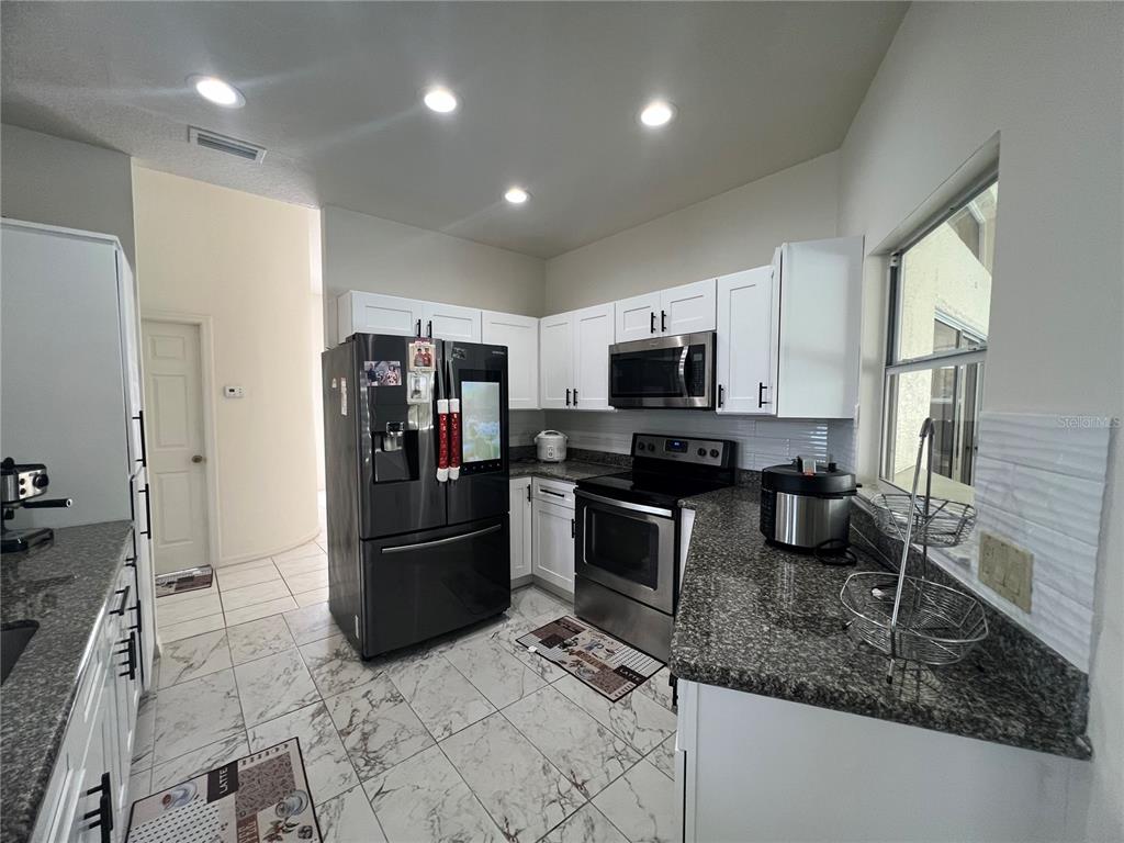 14189 Cornewall Lane Spring Hill, FL 34609 - Photo 15 of 36 a kitchen with refrigerator and microwave