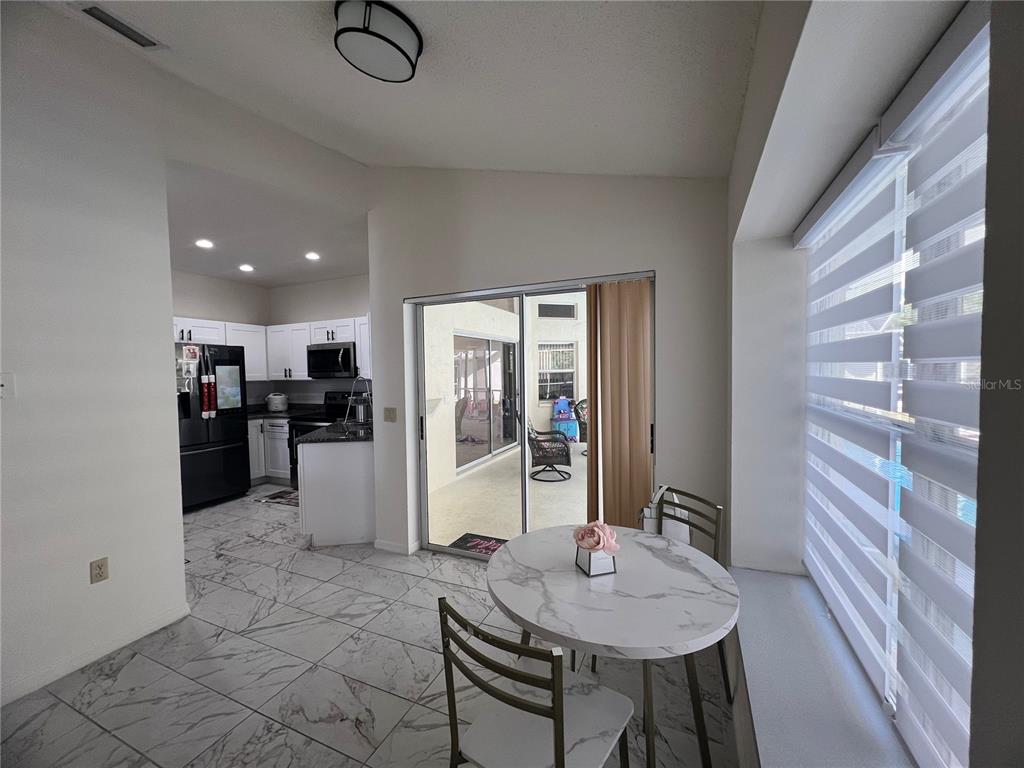 14189 Cornewall Lane Spring Hill, FL 34609 - Photo 16 of 36 a dinning room with stainless steel appliances kitchen island granite countertop a table chairs and a refrigerator