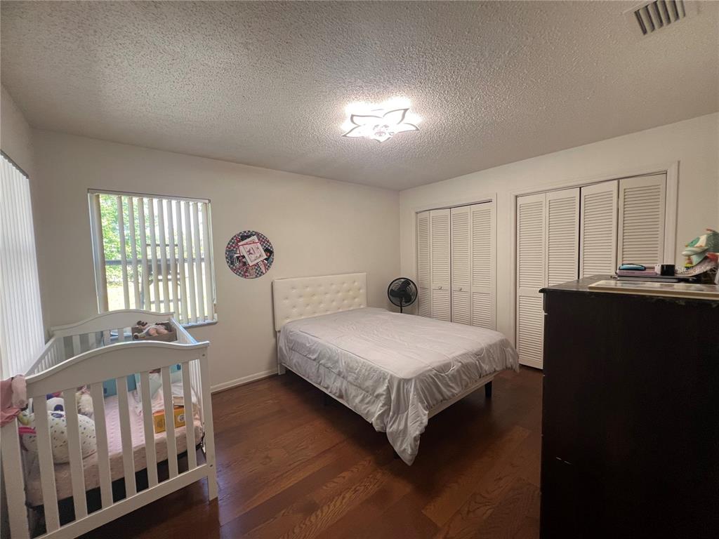 14189 Cornewall Lane Spring Hill, FL 34609 - Photo 25 of 36 a bedroom with a bed a chandelier and dresser