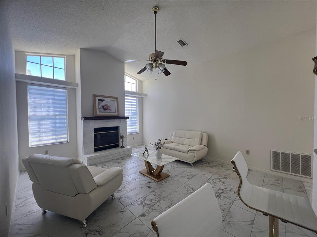 14189 Cornewall Lane Spring Hill, FL 34609 - Photo 9 of 36 a living room with furniture a fireplace and a window