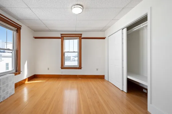 a view of an empty room with window and wooden floor