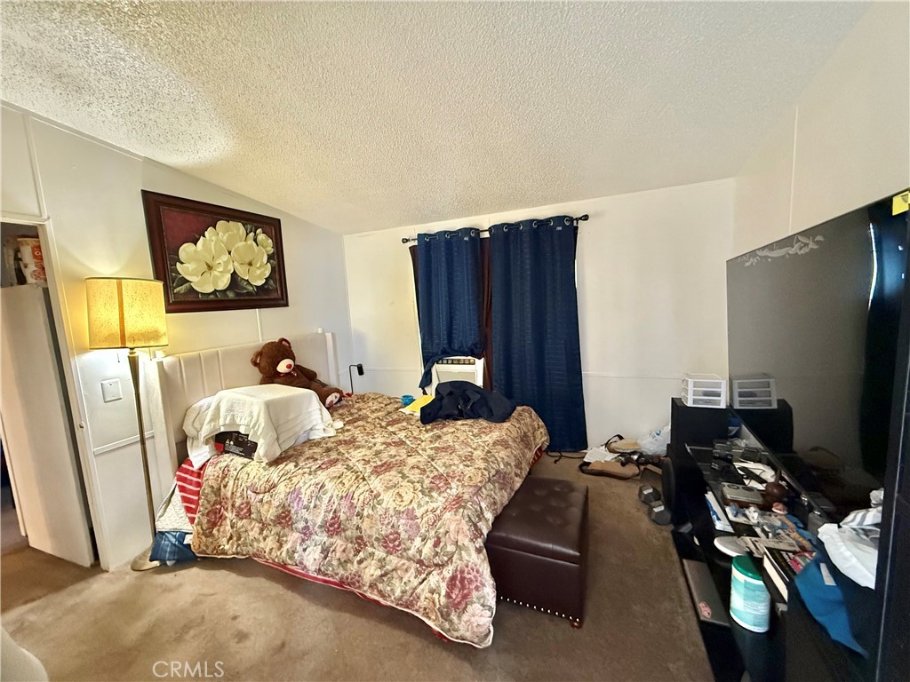 22020 Nisqually Road, Unit 65 Apple Valley, CA 92308 - Photo 12 of 14 a bedroom with bed and a flat screen tv