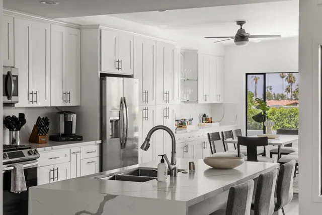 a kitchen with stainless steel appliances granite countertop a stove a sink dishwasher and white cabinets with wooden floor