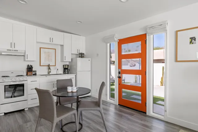 a kitchen with stainless steel appliances granite countertop a stove a refrigerator a dining table and chairs with wooden floor