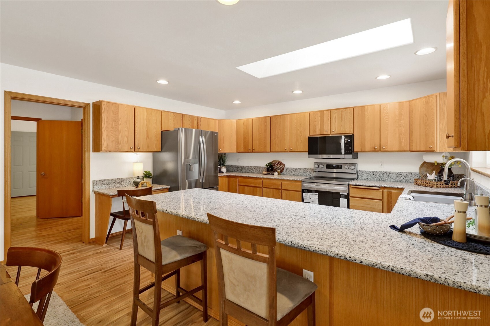 659 Cain Lake Road Sedro-Woolley, WA 98284 - Photo 17 of 40 a kitchen with stainless steel appliances granite countertop a stove top oven a sink a dining table and chairs with wooden floor