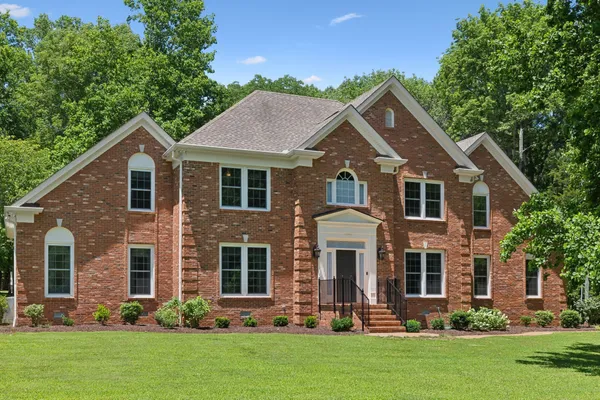 a front view of a house with a yard and trees