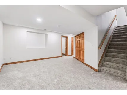a view of an empty room with wooden floor and stairs