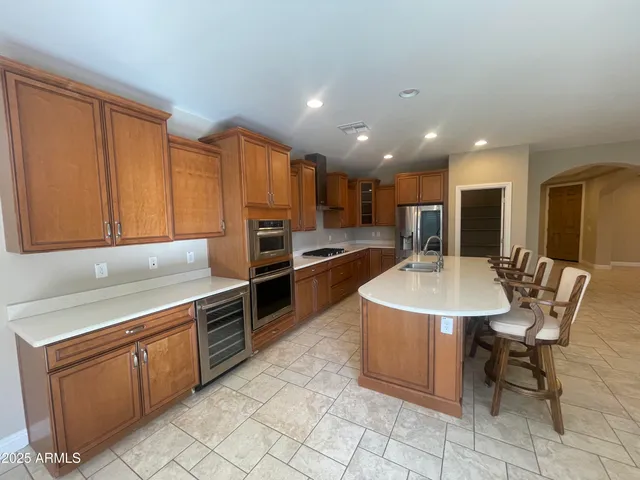 a kitchen with stainless steel appliances granite countertop a sink a stove a refrigerator a microwave cabinets and chairs