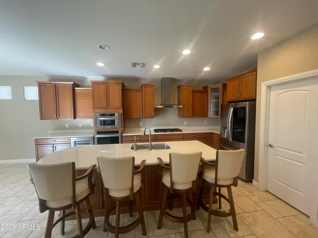 a kitchen with refrigerator a chairs and white cabinets