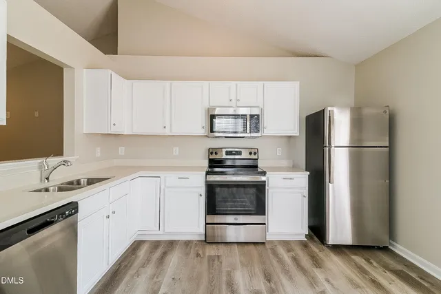 a kitchen with a refrigerator stove and white cabinets