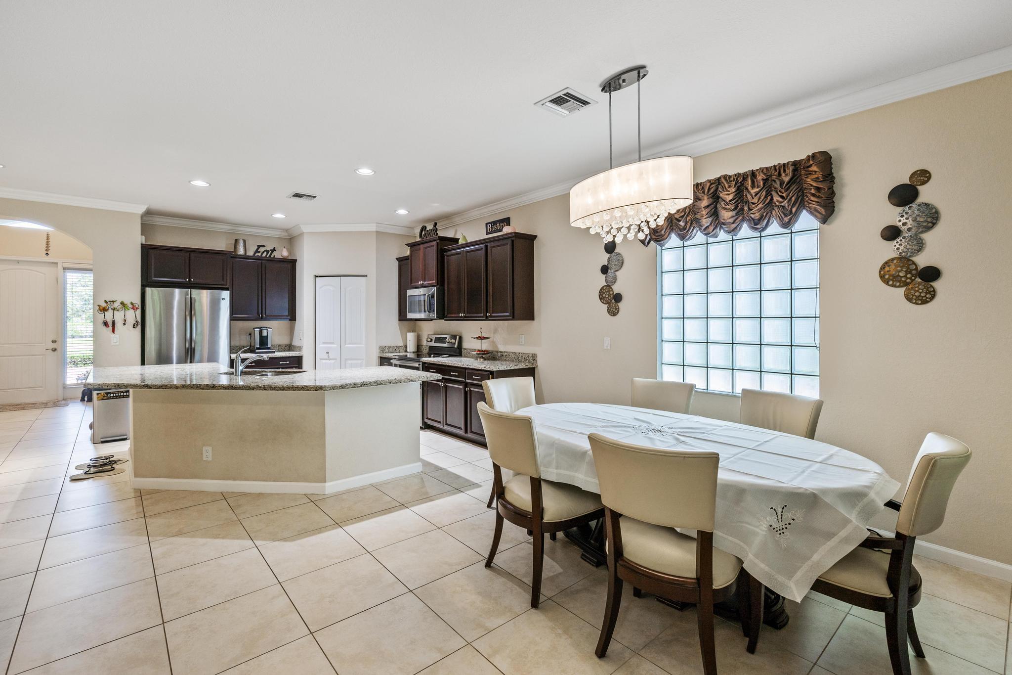 7034 Limestone Cay Road Jupiter, FL 33458 - Photo 13 of 43 a kitchen with granite countertop a table chairs microwave and refrigerator
