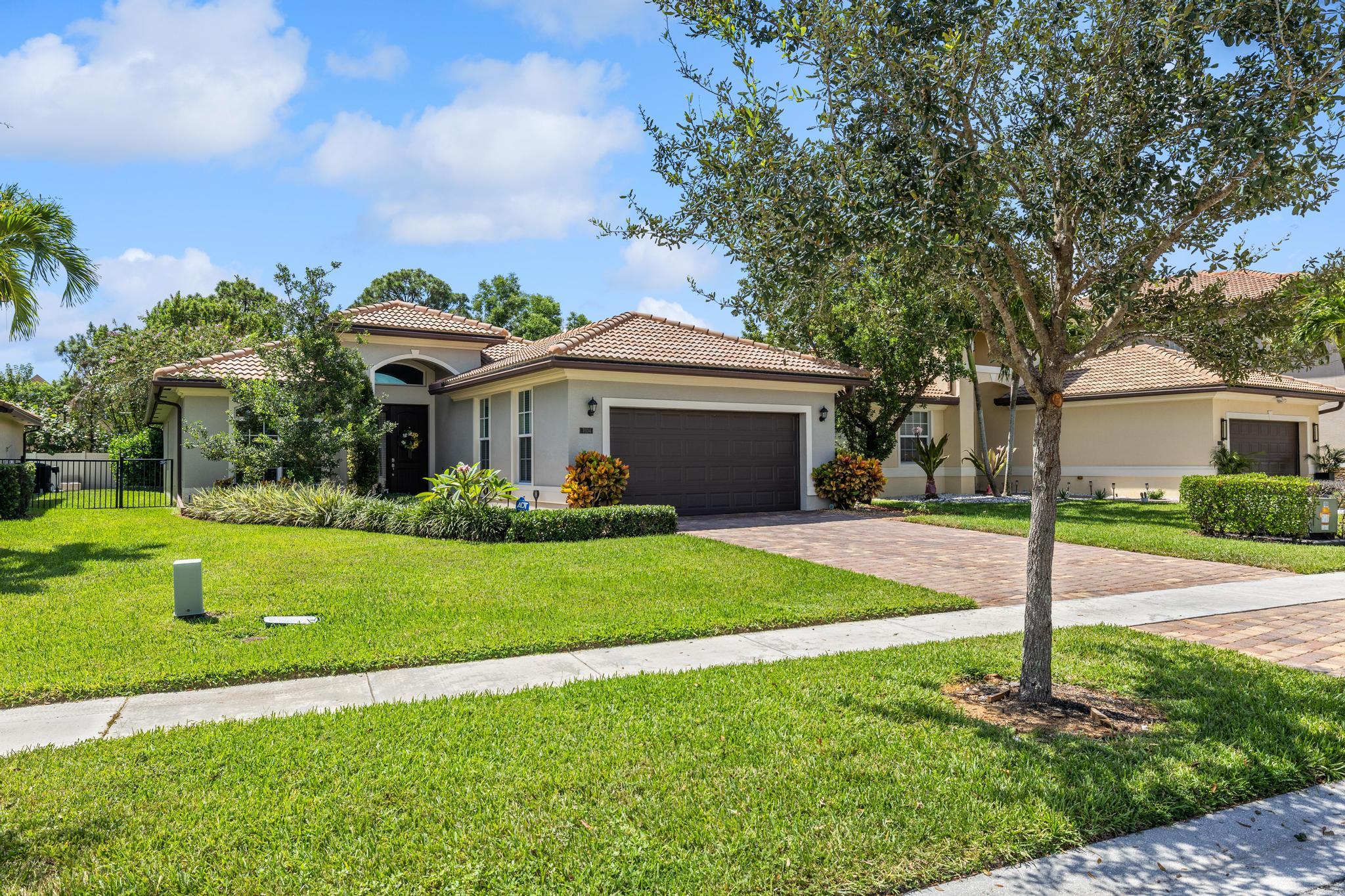 7034 Limestone Cay Road Jupiter, FL 33458 - Photo 3 of 43 a front view of a house with a yard and garage
