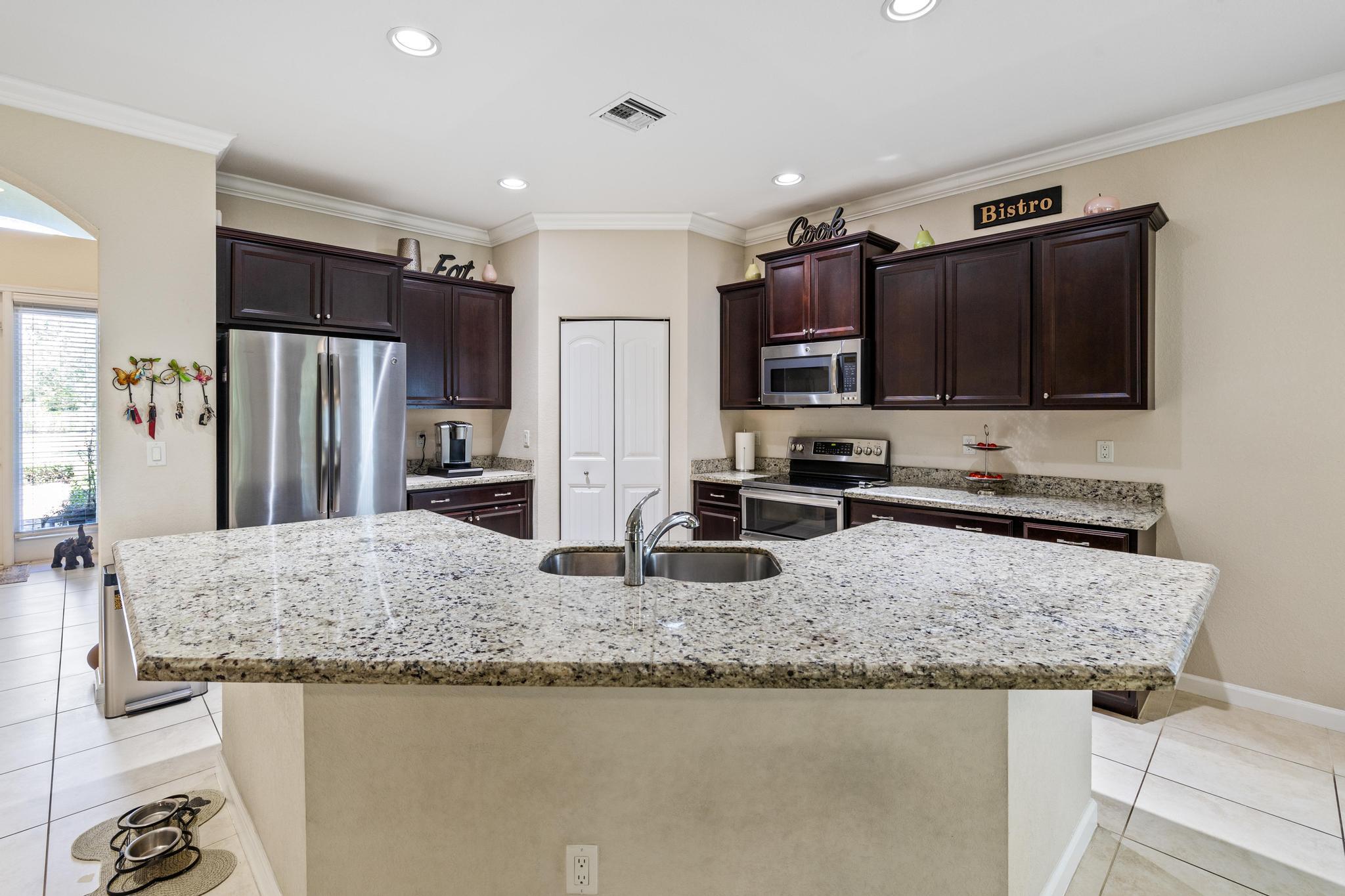 7034 Limestone Cay Road Jupiter, FL 33458 - Photo 9 of 43 a kitchen with stainless steel appliances granite countertop a sink stove and refrigerator
