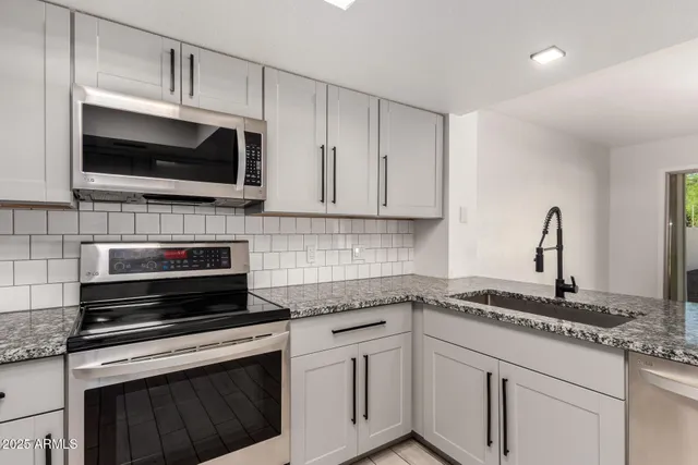 a kitchen with stainless steel appliances granite countertop a sink refrigerator and cabinets