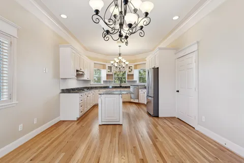 a kitchen with a refrigerator and countertop white cabinets with wooden floor