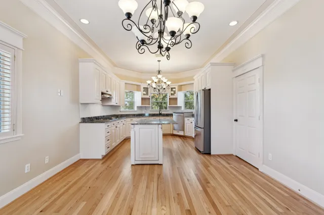 a kitchen with a refrigerator and countertop white cabinets with wooden floor