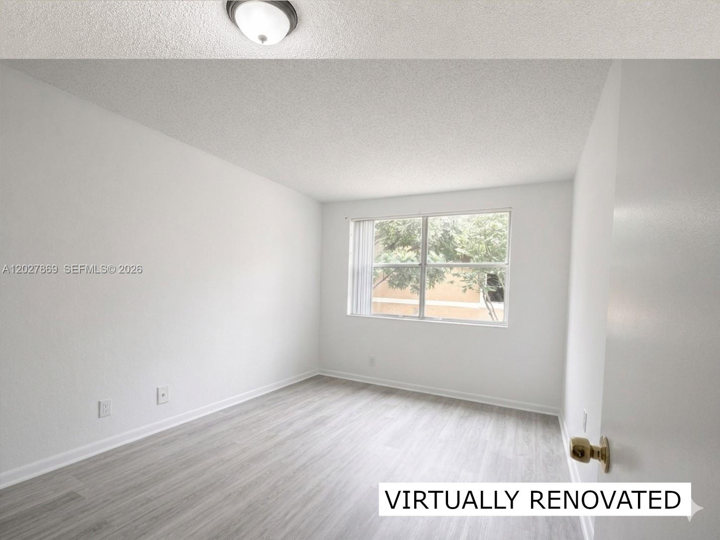 8761 Wiles Road, Unit 206 Coral Springs, FL 33067 - Photo 12 of 26 a view of an empty room with wooden floor and window