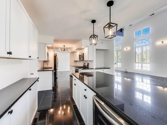 a view of a kitchen with kitchen island stainless steel appliances wooden floor windows and a sink