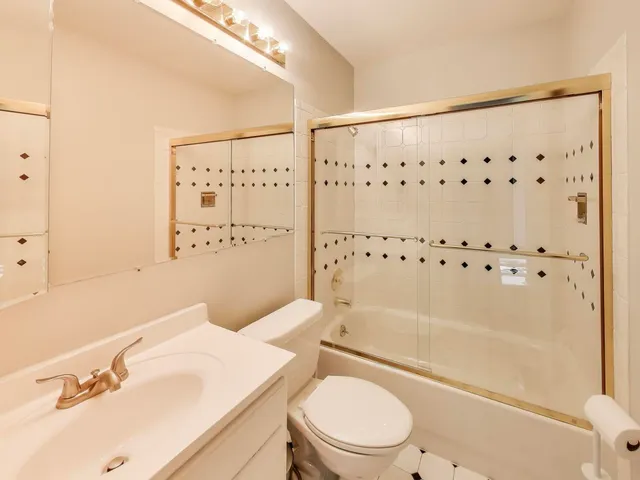 a bathroom with a bathtub shower sink mirror vanity and toilet