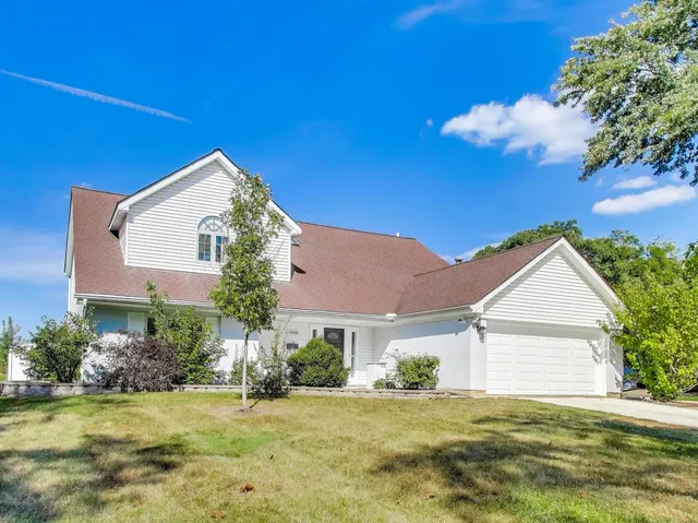 a front view of house with yard and trees in the background
