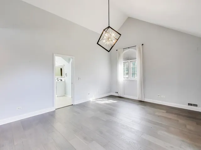 a view of an empty room with wooden floor and window