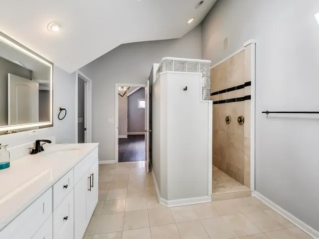 a spacious bathroom with a double vanity sink a mirror and a shower