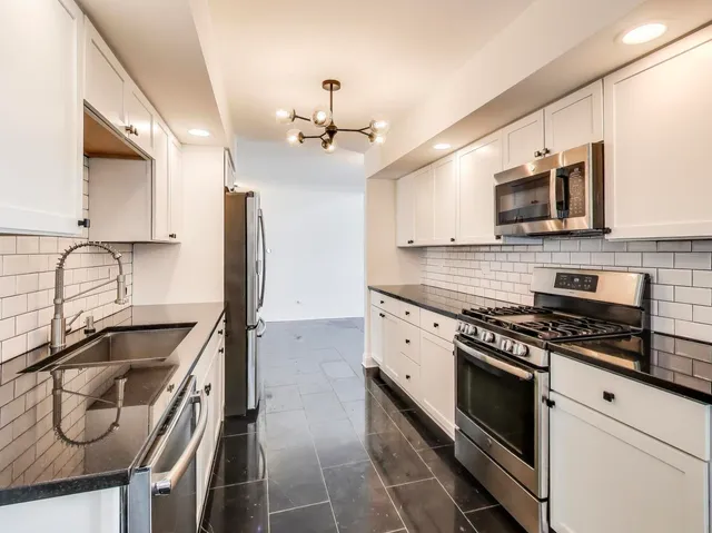 a kitchen with stainless steel appliances granite countertop a sink a stove and cabinets