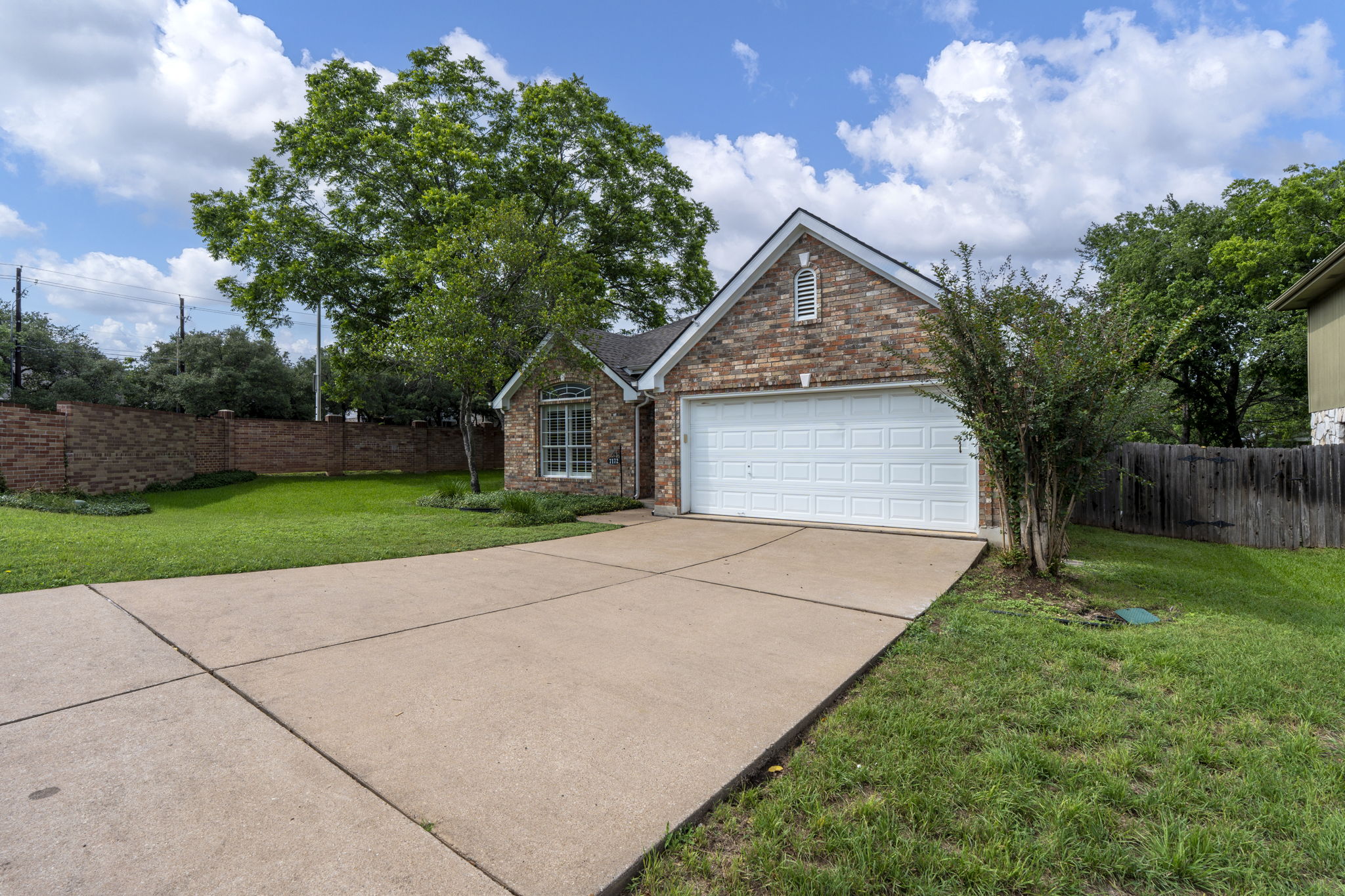 7172 Ridge Oak Road Austin, TX 78749 - Photo 5 of 40 A well-maintained brick facade home awaits, featuring an attached garage and a concrete driveway amidst lush green landscaping.
