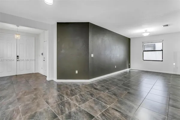 an empty room with windows and way to kitchen