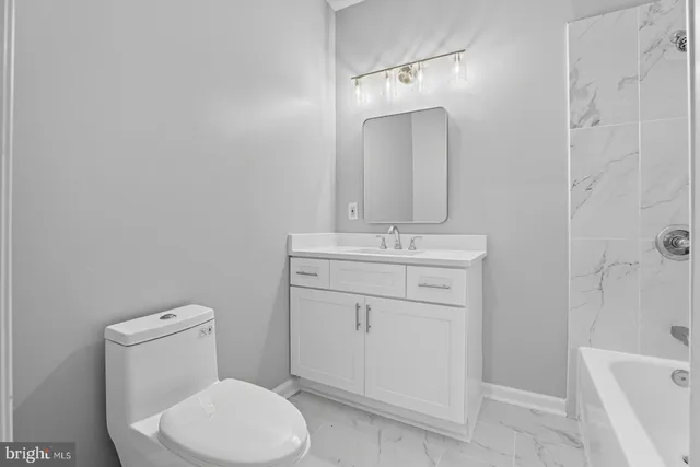 a bathroom with a toilet sink vanity and tub