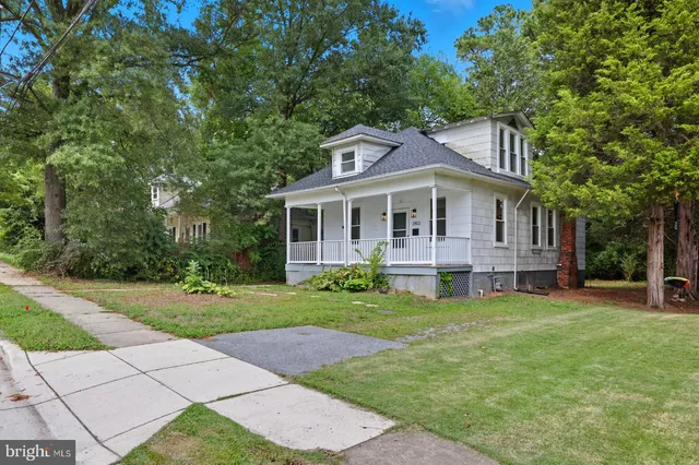a front view of a house with a garden and trees