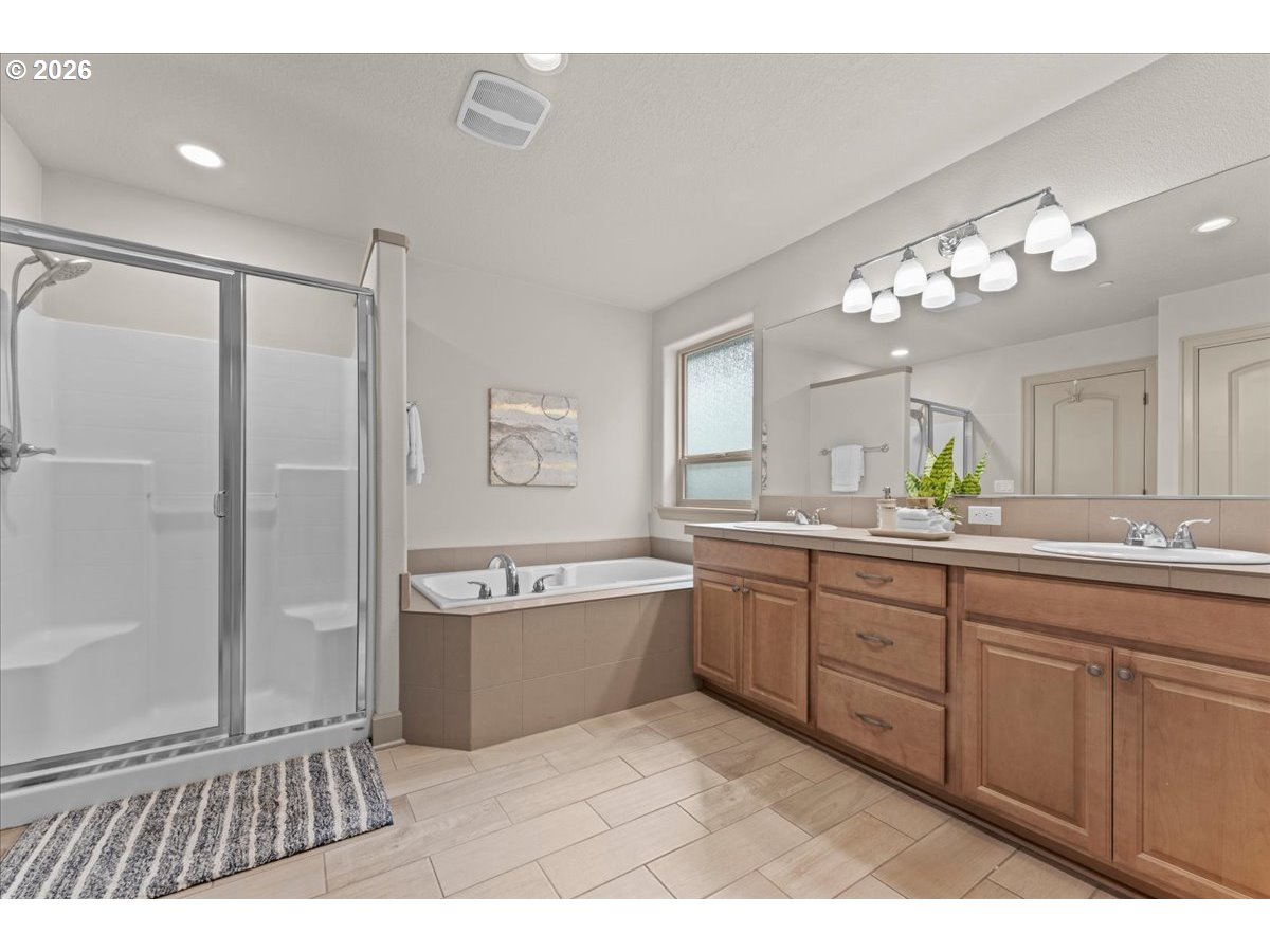 10899 Southwest Barber Street Wilsonville, OR 97070 - Photo 24 of 44 a spacious bathroom with a granite countertop sink a mirror a bathtub and shower