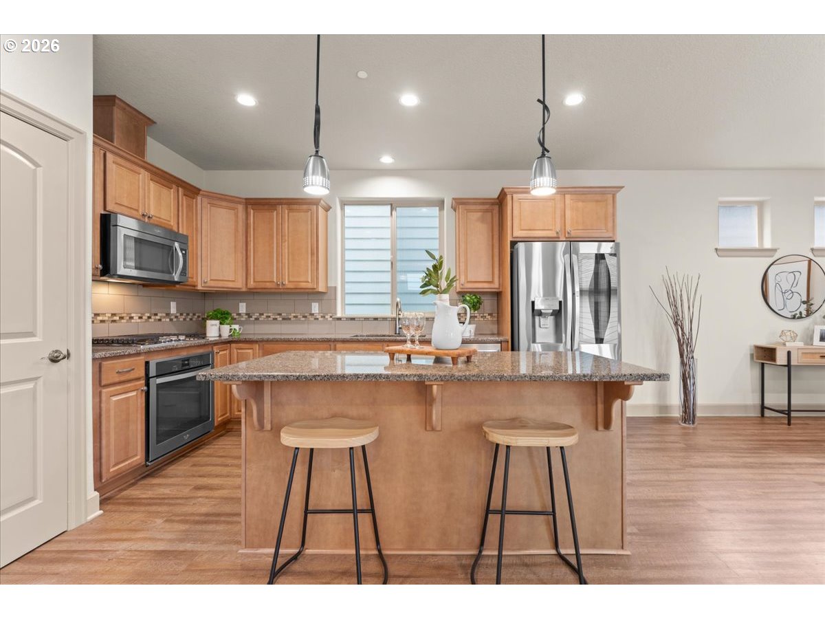 10899 Southwest Barber Street Wilsonville, OR 97070 - Photo 9 of 44 a kitchen with stainless steel appliances kitchen island granite countertop a sink a stove a dining table and chairs