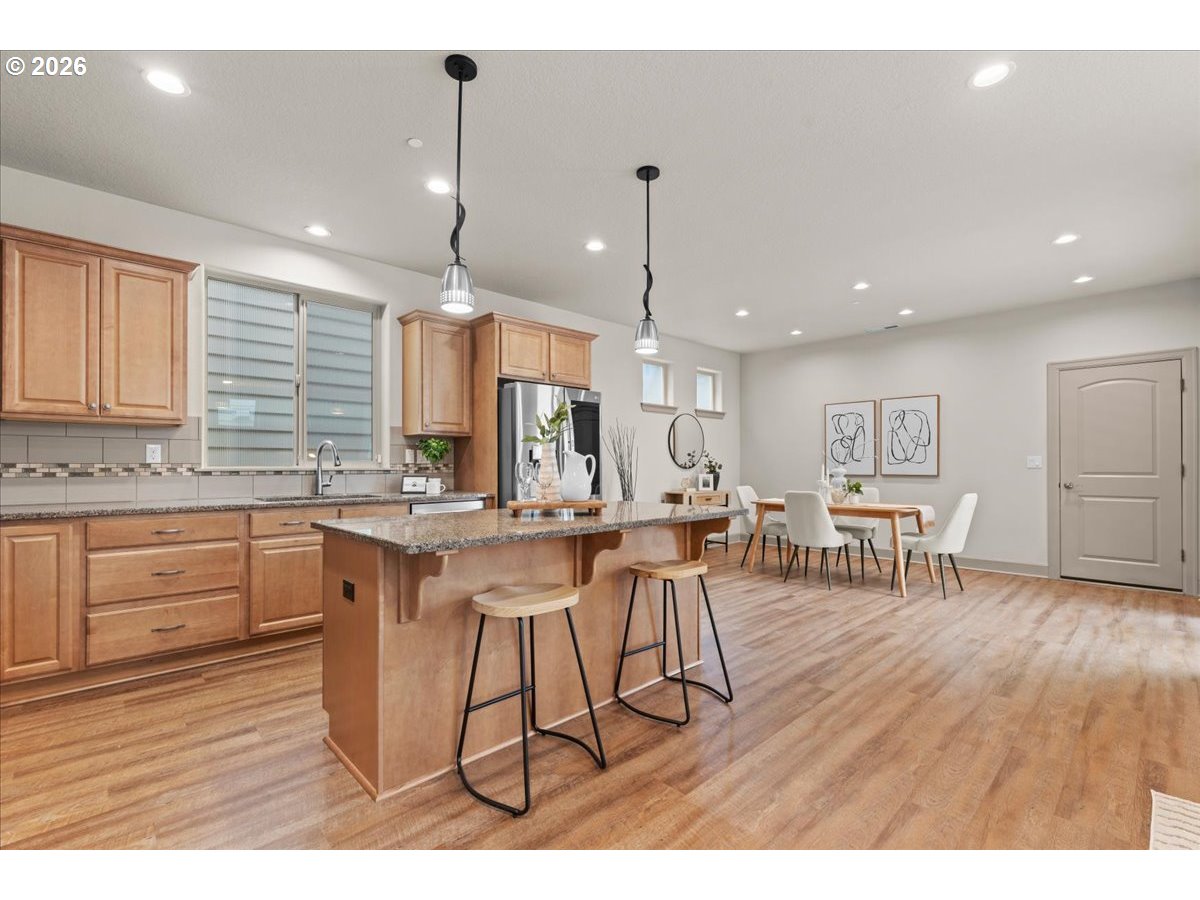 10899 Southwest Barber Street Wilsonville, OR 97070 - Photo 10 of 44 a open kitchen with stainless steel appliances granite countertop a dining table chairs stove a refrigerator and cabinets
