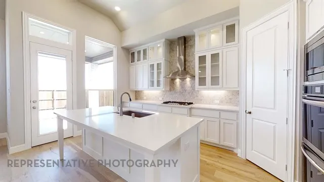a kitchen with a sink a stove a refrigerator and white cabinets