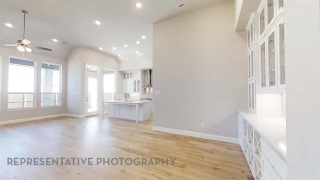 a view of an empty room and a kitchen with a sink wooden floor