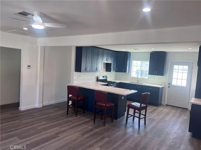 a kitchen with stainless steel appliances granite countertop a dining table chairs refrigerator sink and cabinets