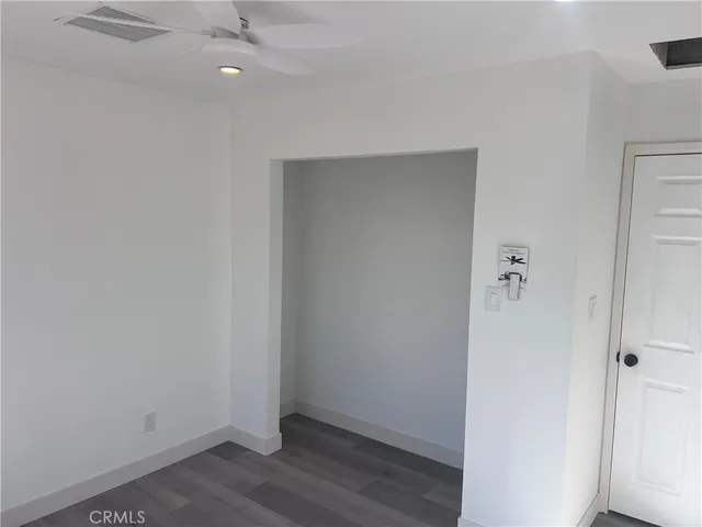 an empty room with wooden floor and fan